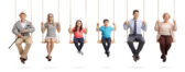 Grandparents, parents and children sitting on swings and smiling